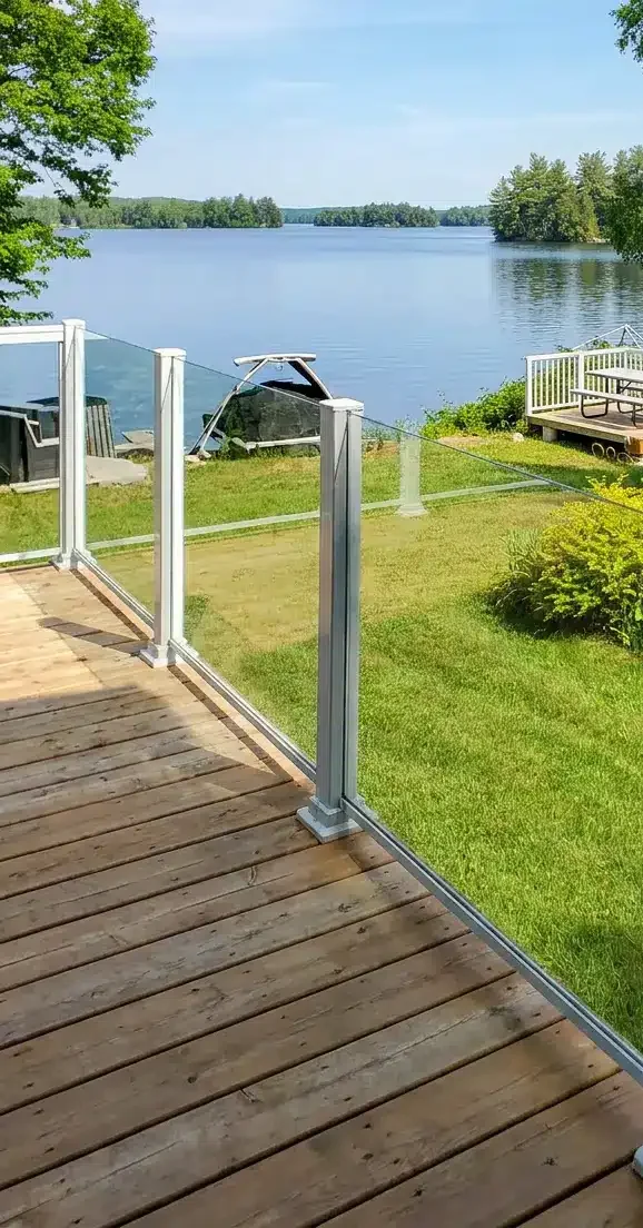 Terrasse résidentielle avec rampes en verre et aluminium offrant une vue dégagée sur la cour arrière.