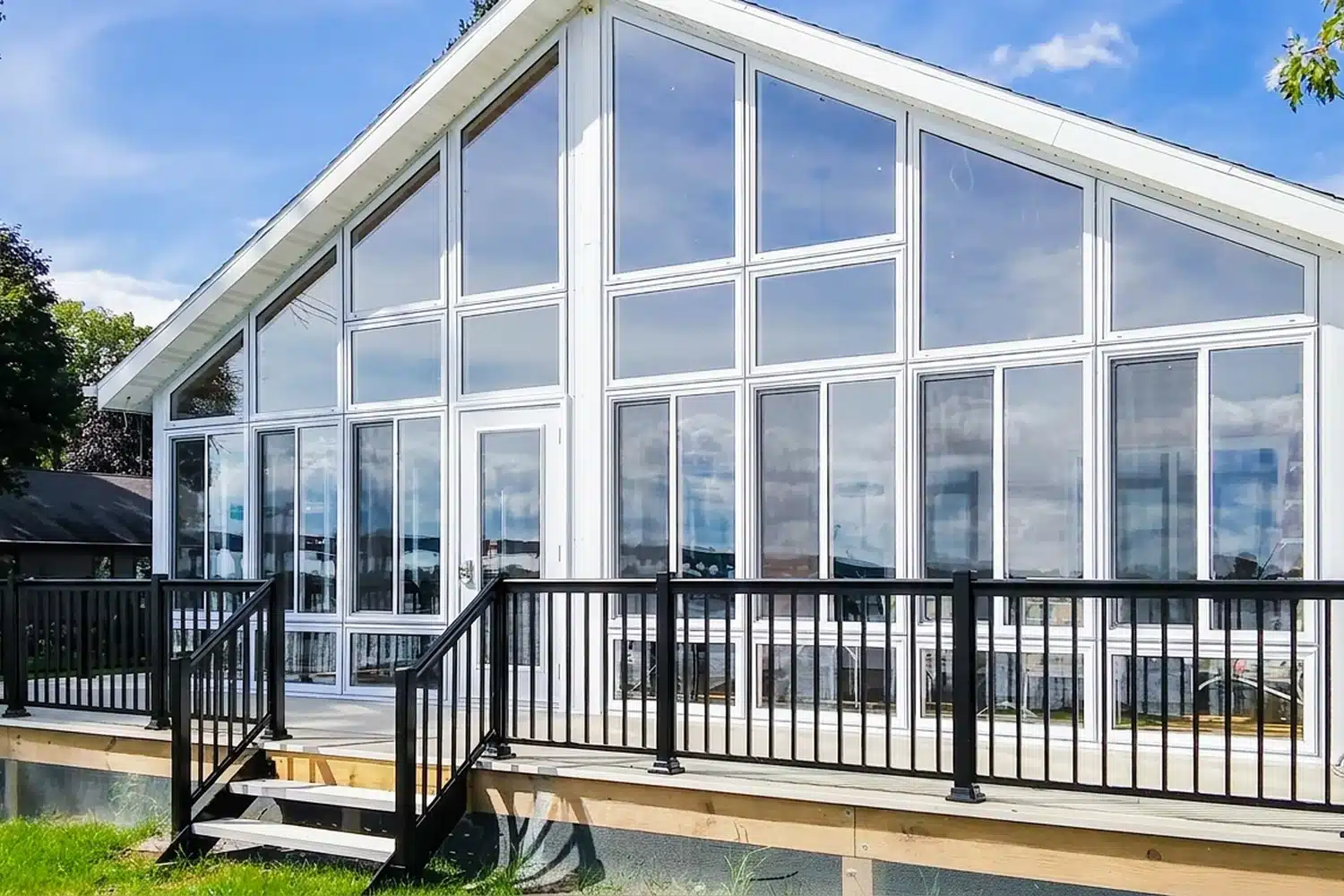 Solarium 3 saisons en verre installé sur une terrasse avec rampe noire