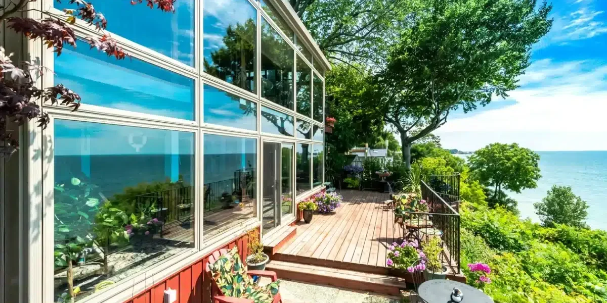Façade vitrée d’un solarium trois saisons sur une terrasse au bord de l’eau